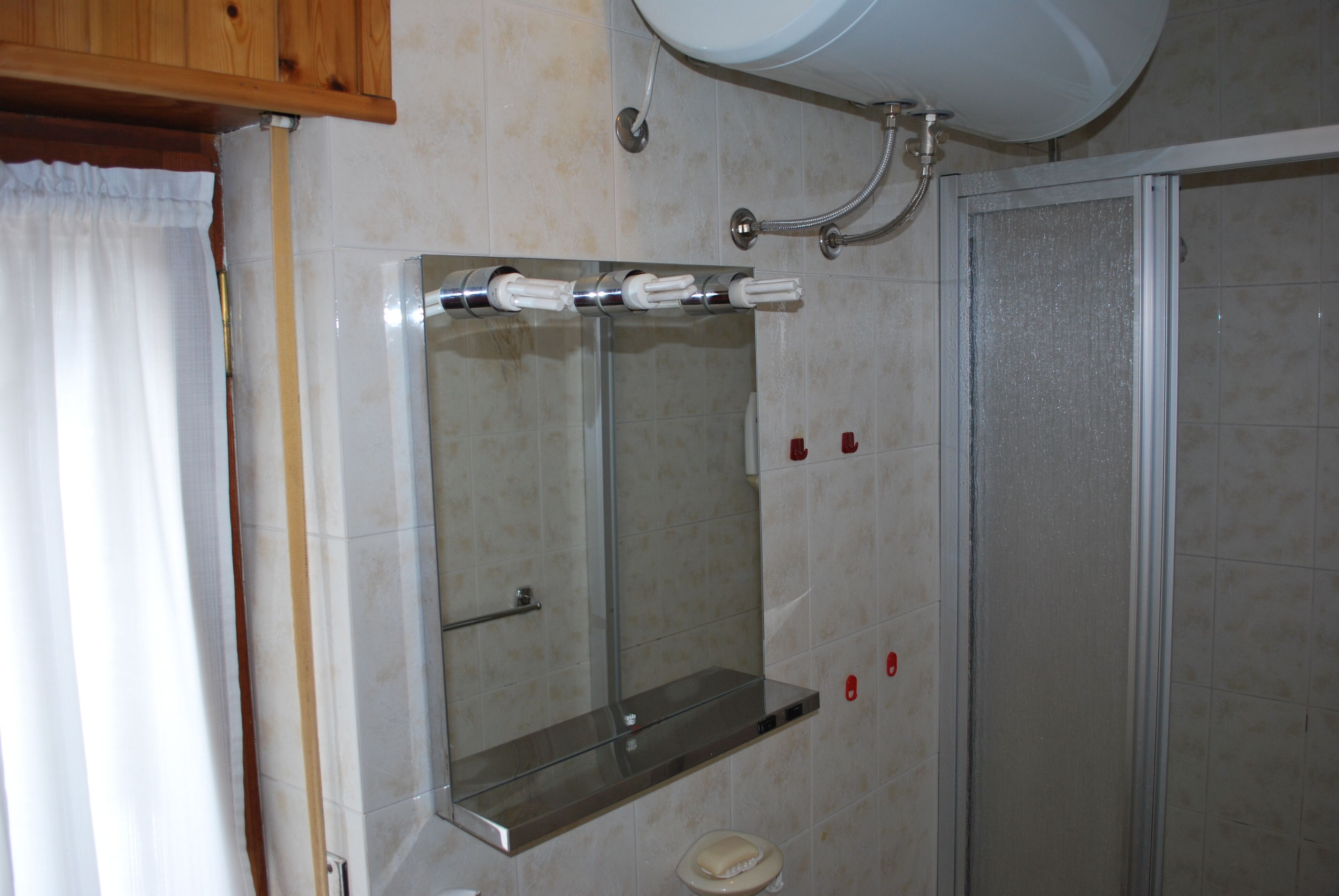 Un baño con cabina de ducha de vidrio, espejo y perchero.