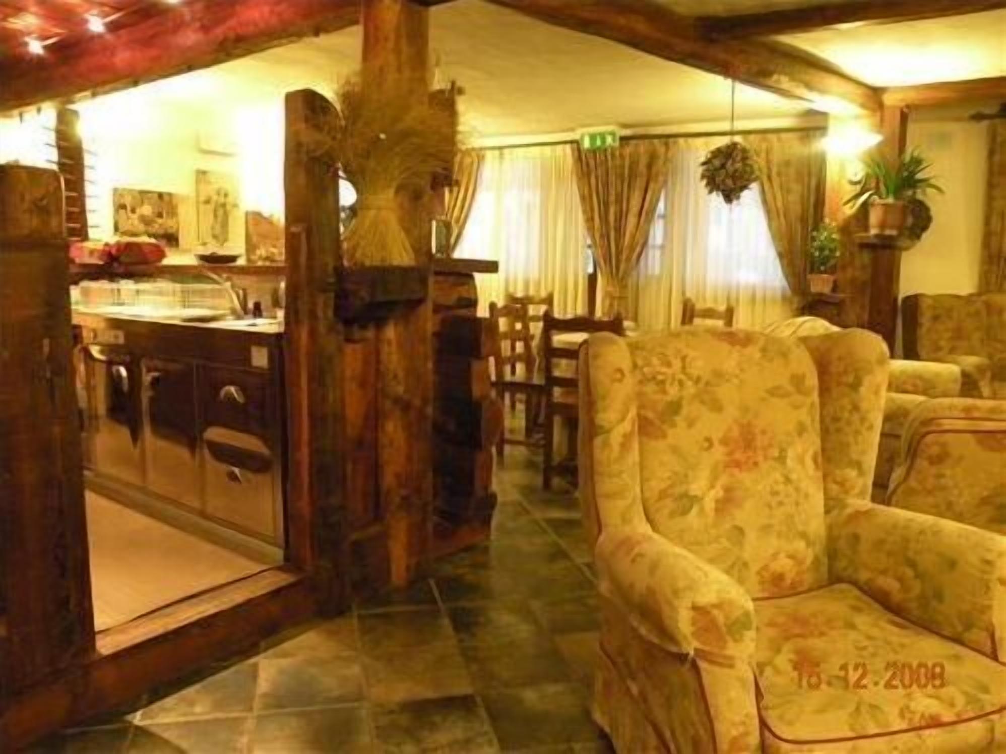 A cozy room with a wooden pillar, a floral armchair, and a dining area with a table and chairs.