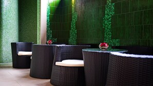 A row of wicker lounge chairs with cushions, arranged in a semi-circle around a central table with a vase of flowers. - Best Baltic Hotel Palanga (Palanga)
