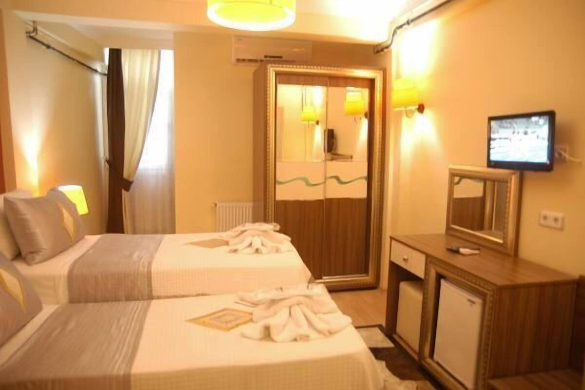 A hotel room with two beds, a wooden wardrobe, a television, and a mirror.