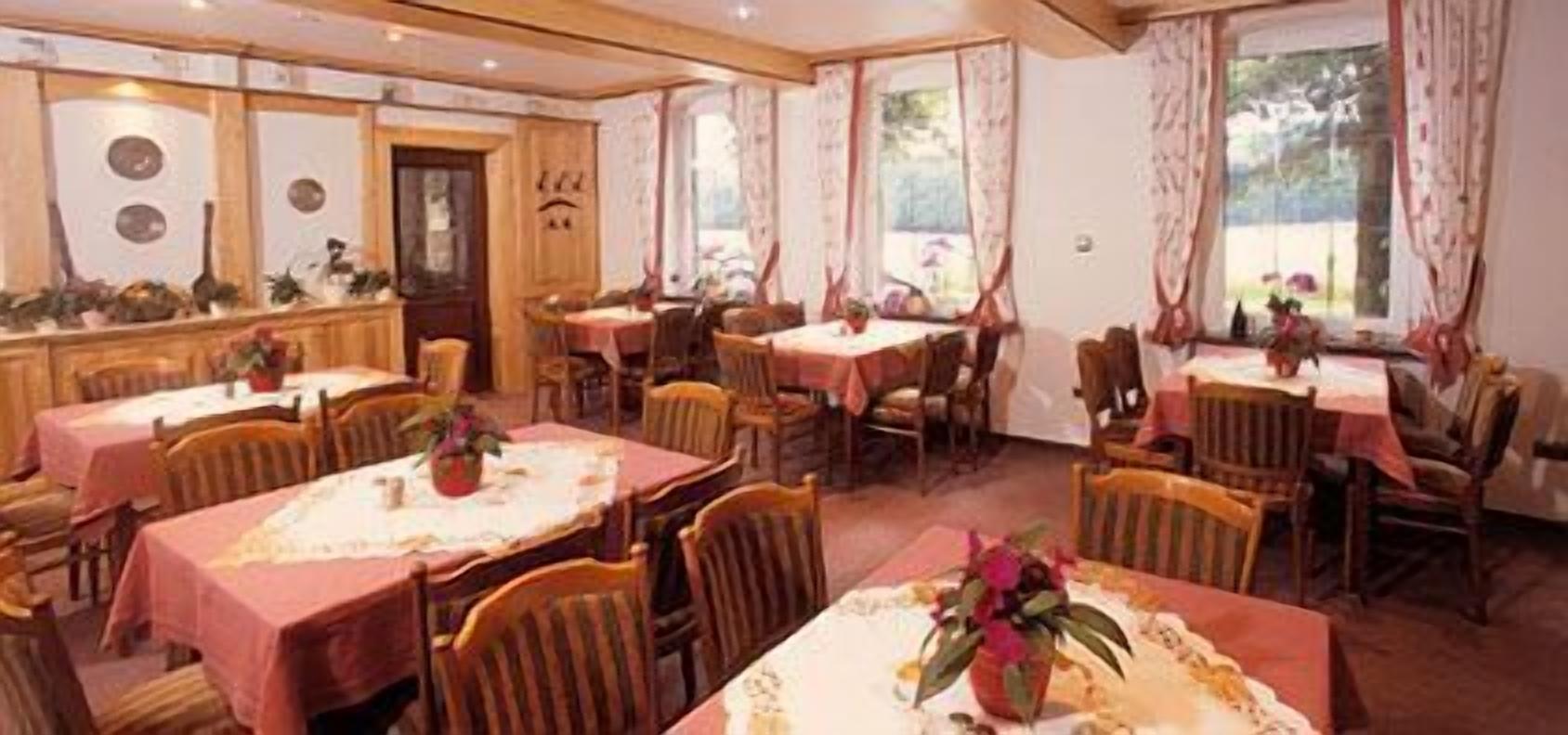 Un'area pranzo con diversi tavoli, sedie e un bancone in legno con oggetti decorativi.