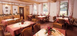 A dining area with multiple tables, chairs, and a wooden counter with decorative items. - Stössel's Hotel & Restaurant (Altenmedingen)