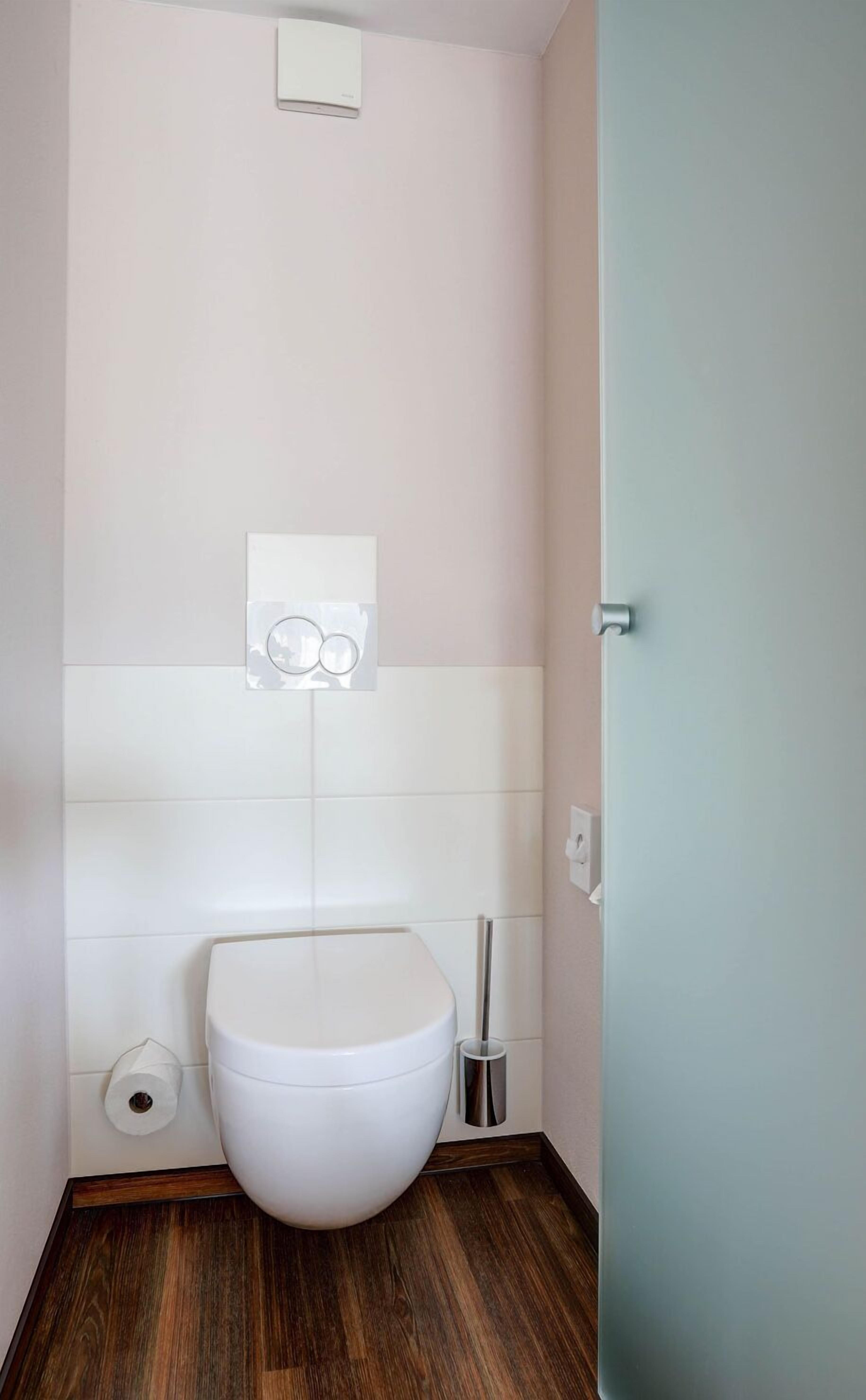 Une petite salle de bain moderne avec des toilettes blanches, un porte-rouleau de papier toilette et un bidet.