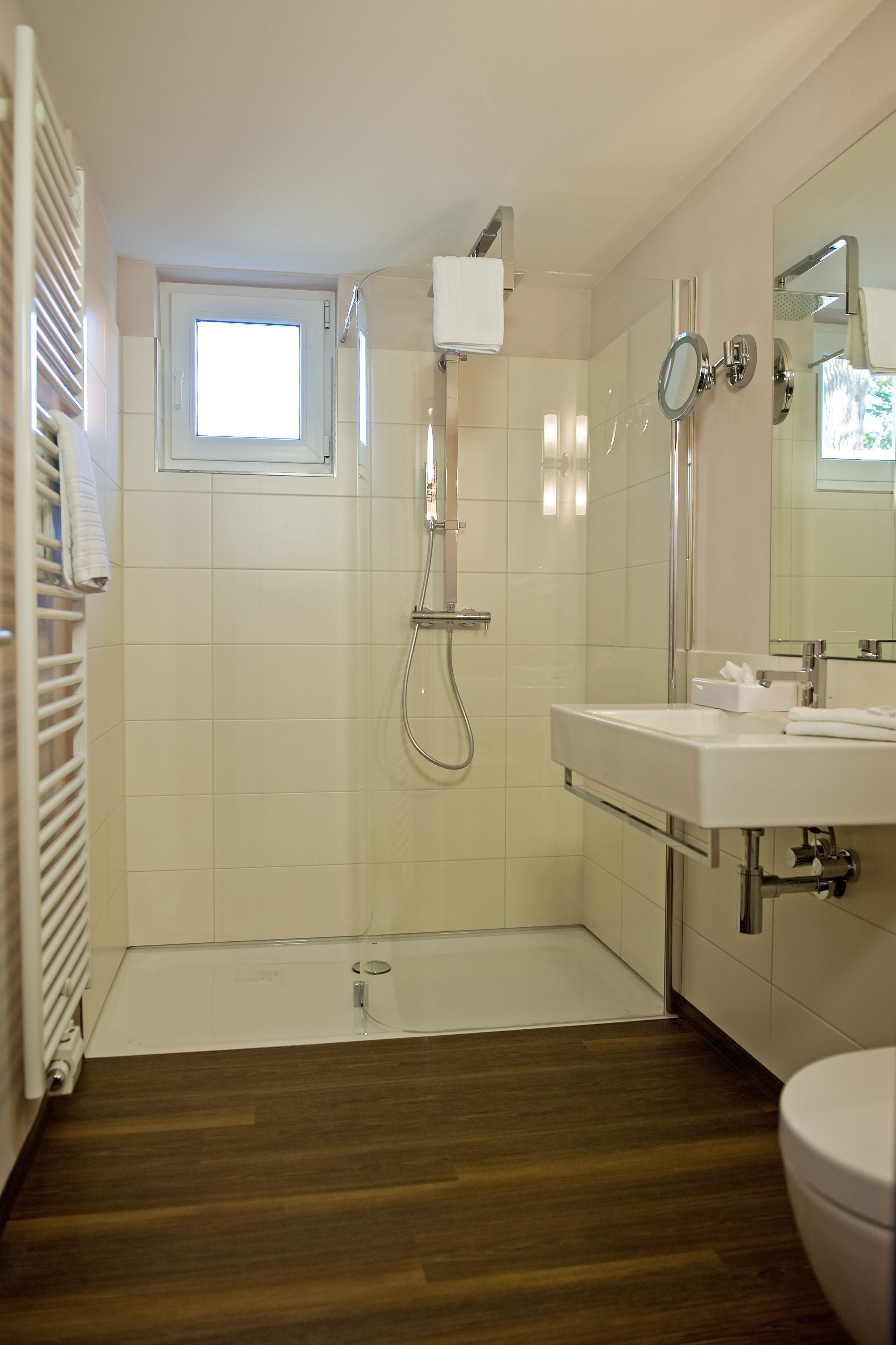 Un baño moderno con cabina de ducha de vidrio, un lavamanos blanco y un inodoro.