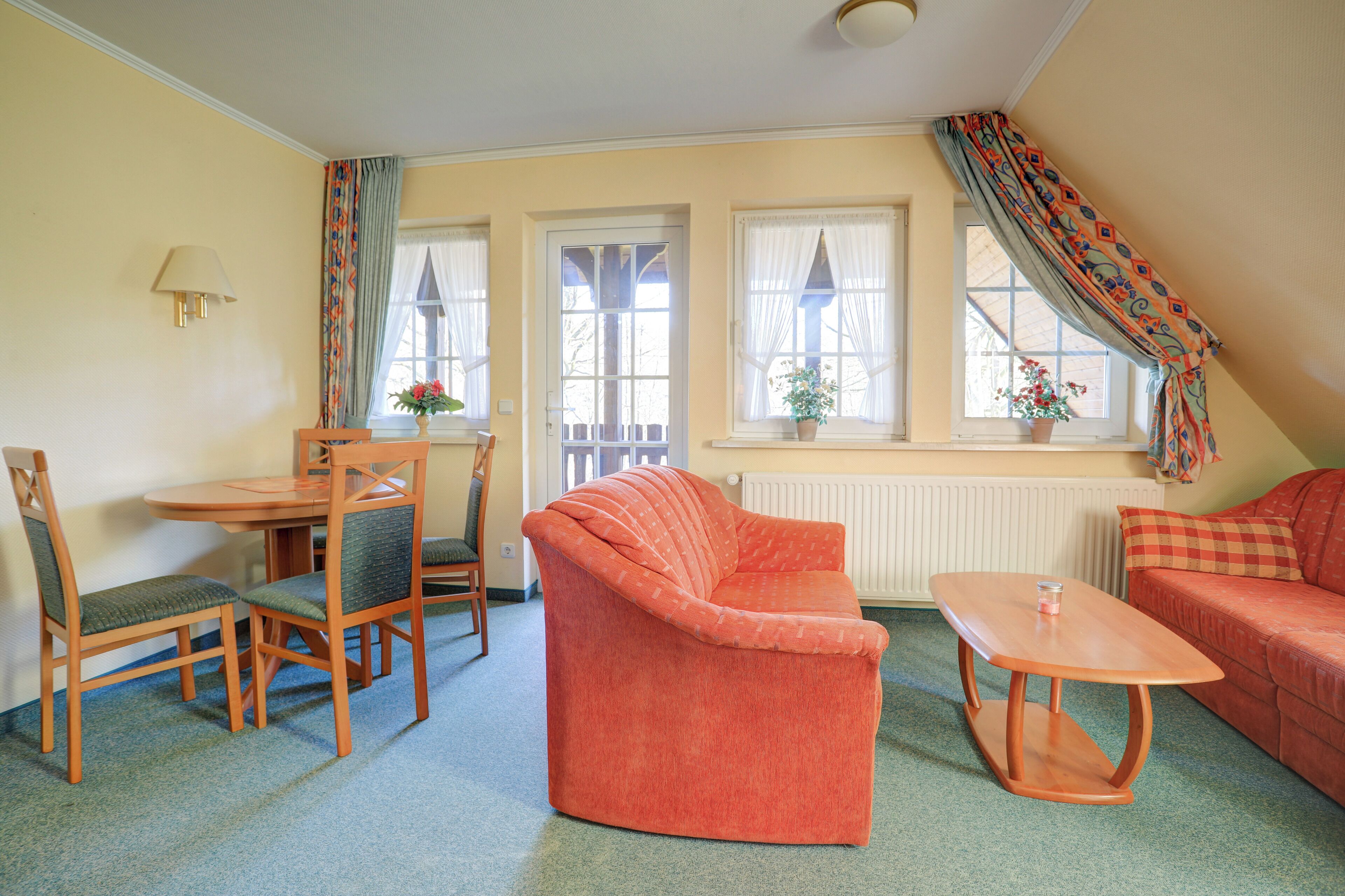 Una habitación acogedora con un sofá, una mesa de comedor con sillas y una ventana con cortinas.