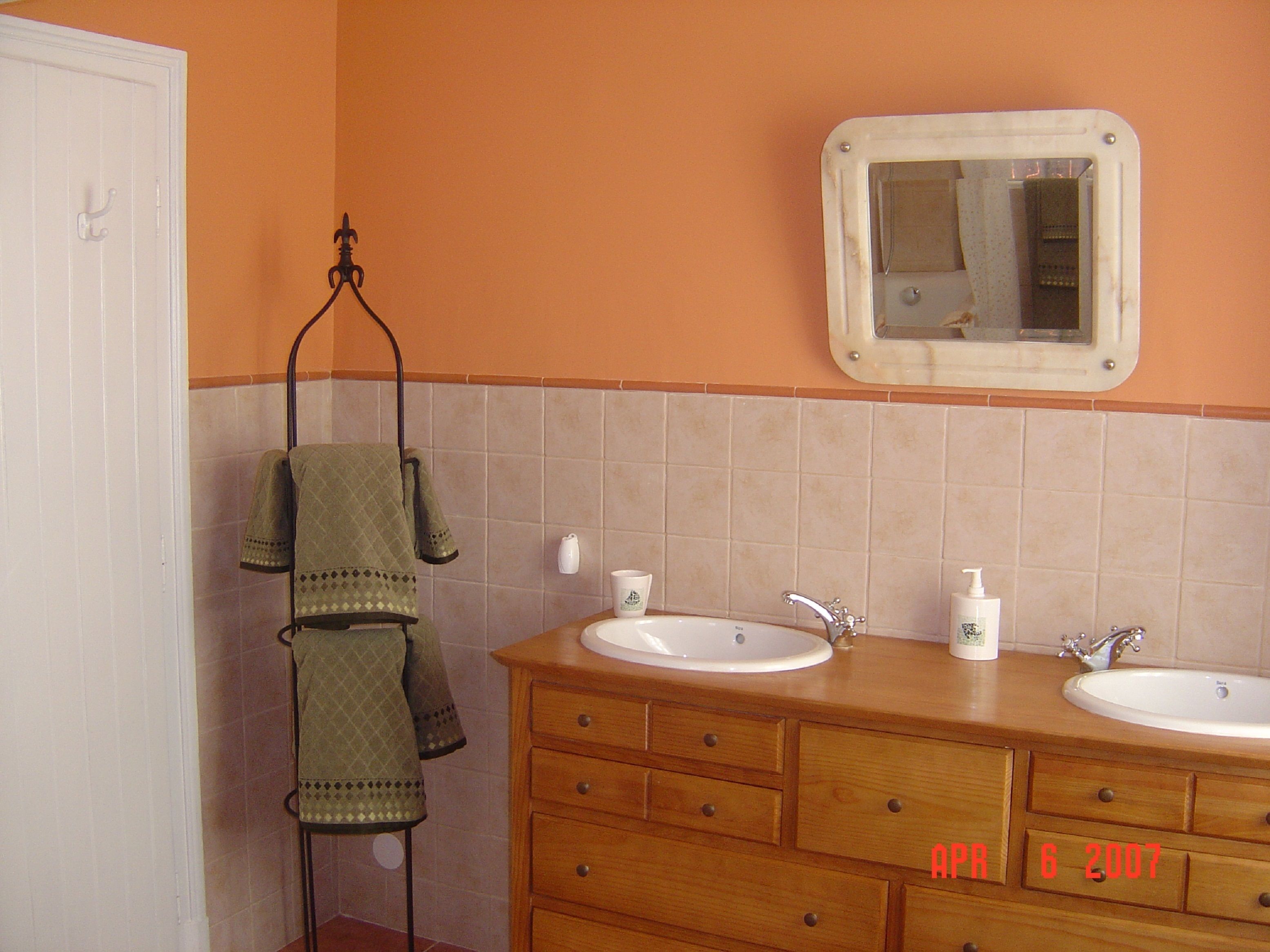 Ein Badezimmer mit zwei Waschbecken, einem Spiegel und einem Handtuchhalter.