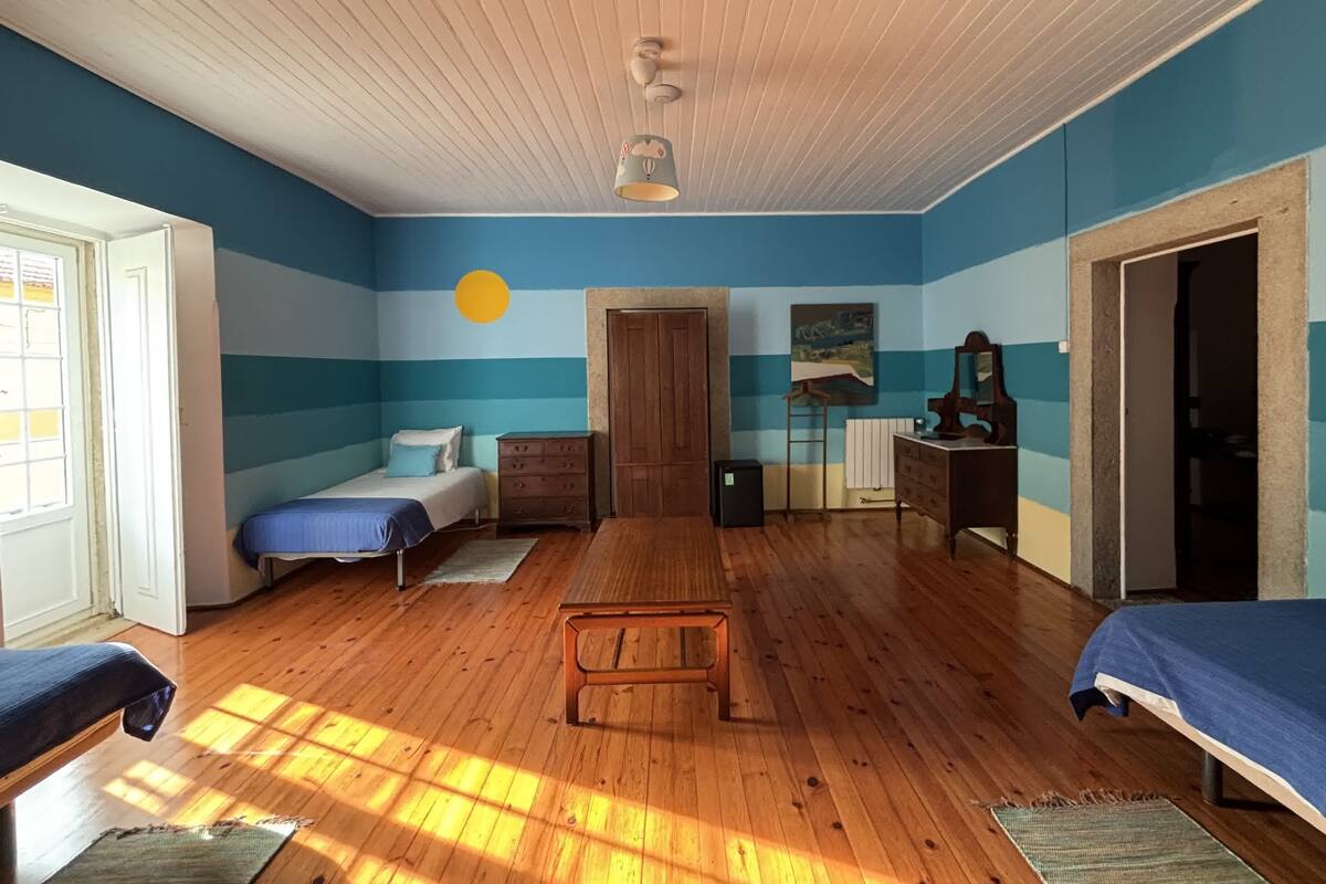 A room with wooden flooring, a bed, a dresser, and a desk.