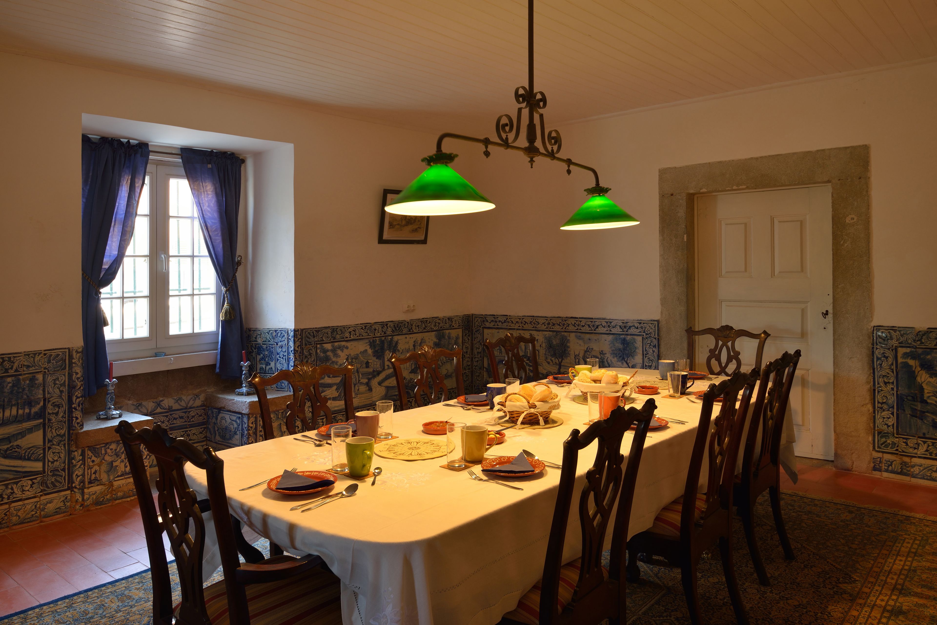 A dining room with a long table set for a meal, surrounded by wooden chairs.