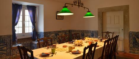 A dining room with a long table set for a meal, surrounded by wooden chairs.