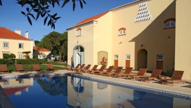 A swimming pool with lounge chairs and a building with a red roof and beige walls. - Quinta do Scoto (Sintra)