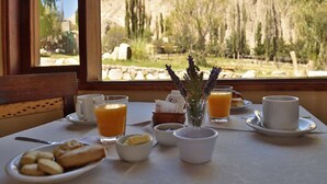 A breakfast table with a view of a mountainous landscape through a window. - Hotel El Reposo del Diablo (Tilcara)