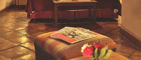 Una habitación de hotel con una cama, una mesita de noche, una pequeña mesa con una revista y tres velas encendidas.