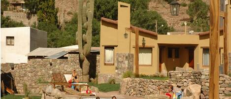 A pool area with stone walls and a wooden deck, surrounded by buildings and cacti.