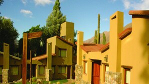 A courtyard with yellow buildings, stone accents, and a central wooden pergola. - Hotel El Reposo del Diablo (Tilcara)