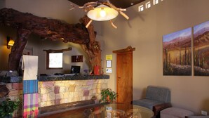 A lobby with a stone wall, wooden ceiling, a glass table, and a painting on the wall. - Hotel El Reposo del Diablo (Tilcara)