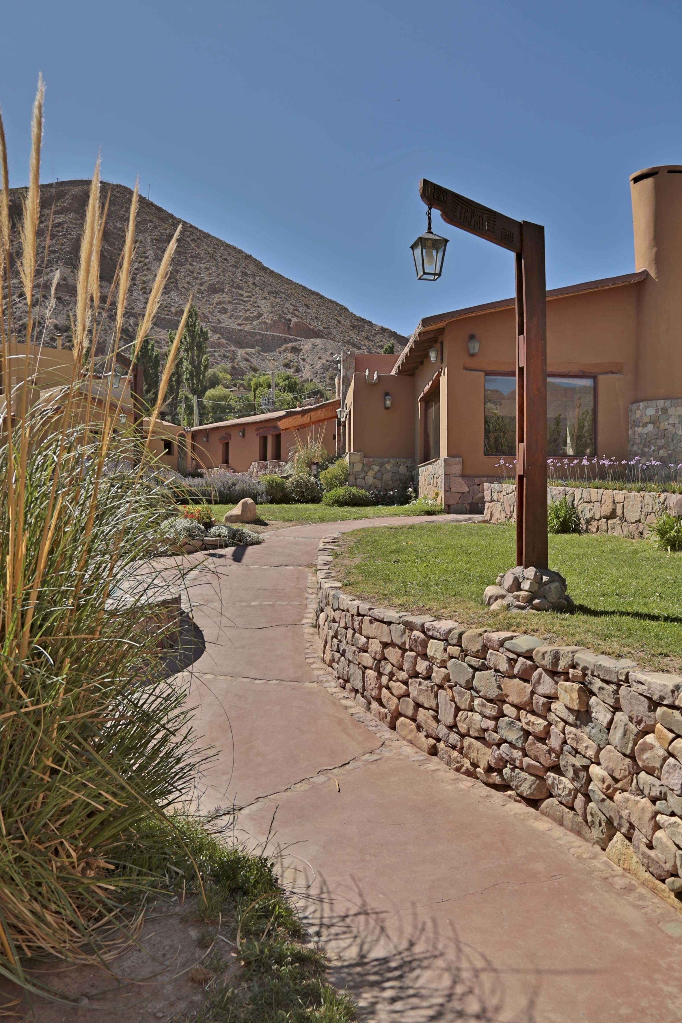 A pathway leading to a building with a stone wall and a hanging lantern.
