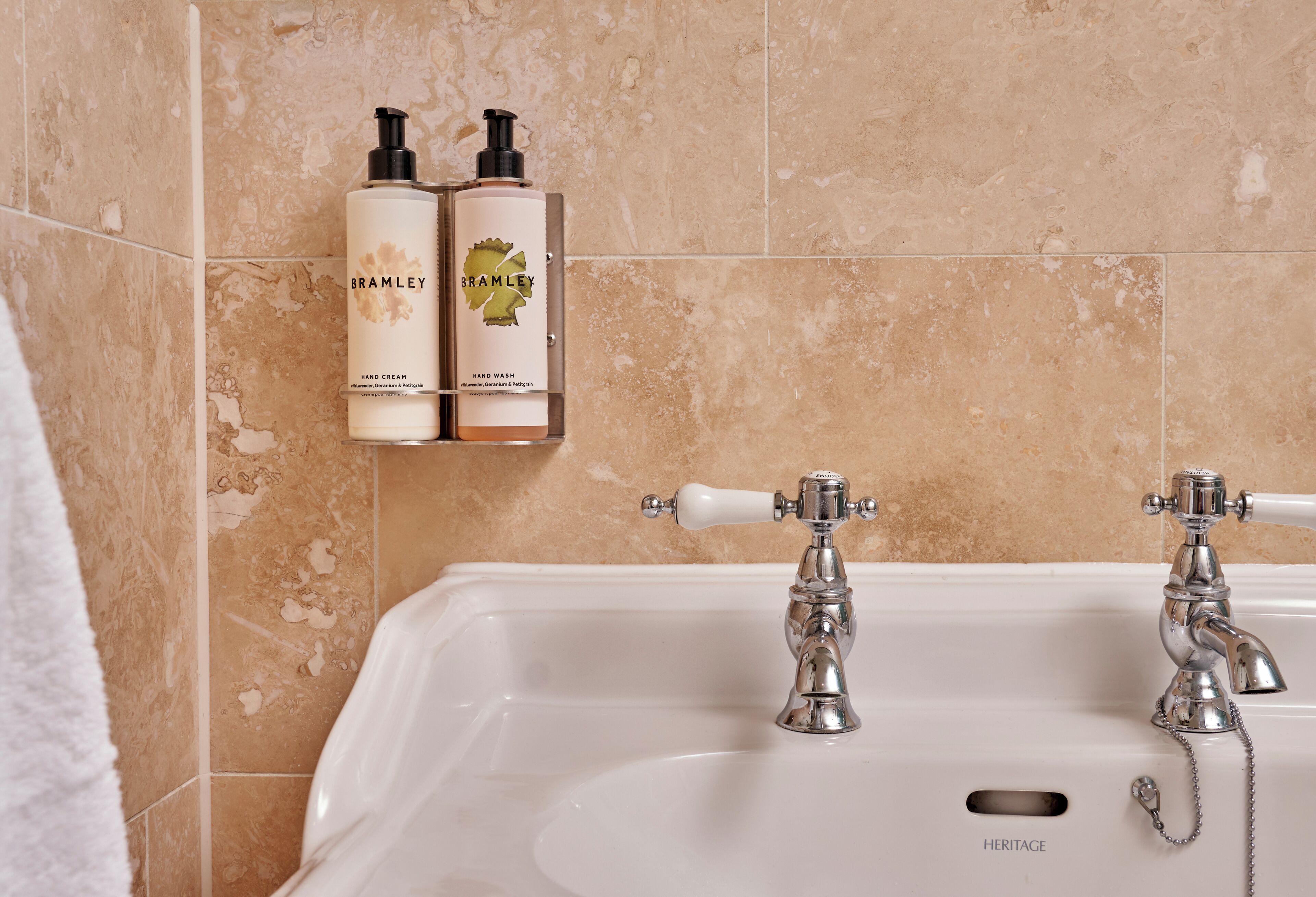 Ein Badezimmer mit einer Badewanne, zwei Flaschen Bramble Handcreme und einem historischen Waschbecken.