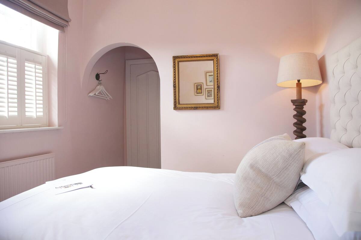 A bedroom with a bed, a lamp, a mirror, and a radiator.