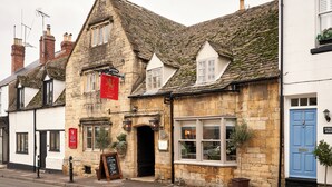 A traditional stone building with a black door, a red sign, and a blue door. - The Lion Inn (Cheltenham)