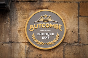 A circular sign with the text "BUTCOMBE BOUTIQUE INNS" and a bridge illustration.
