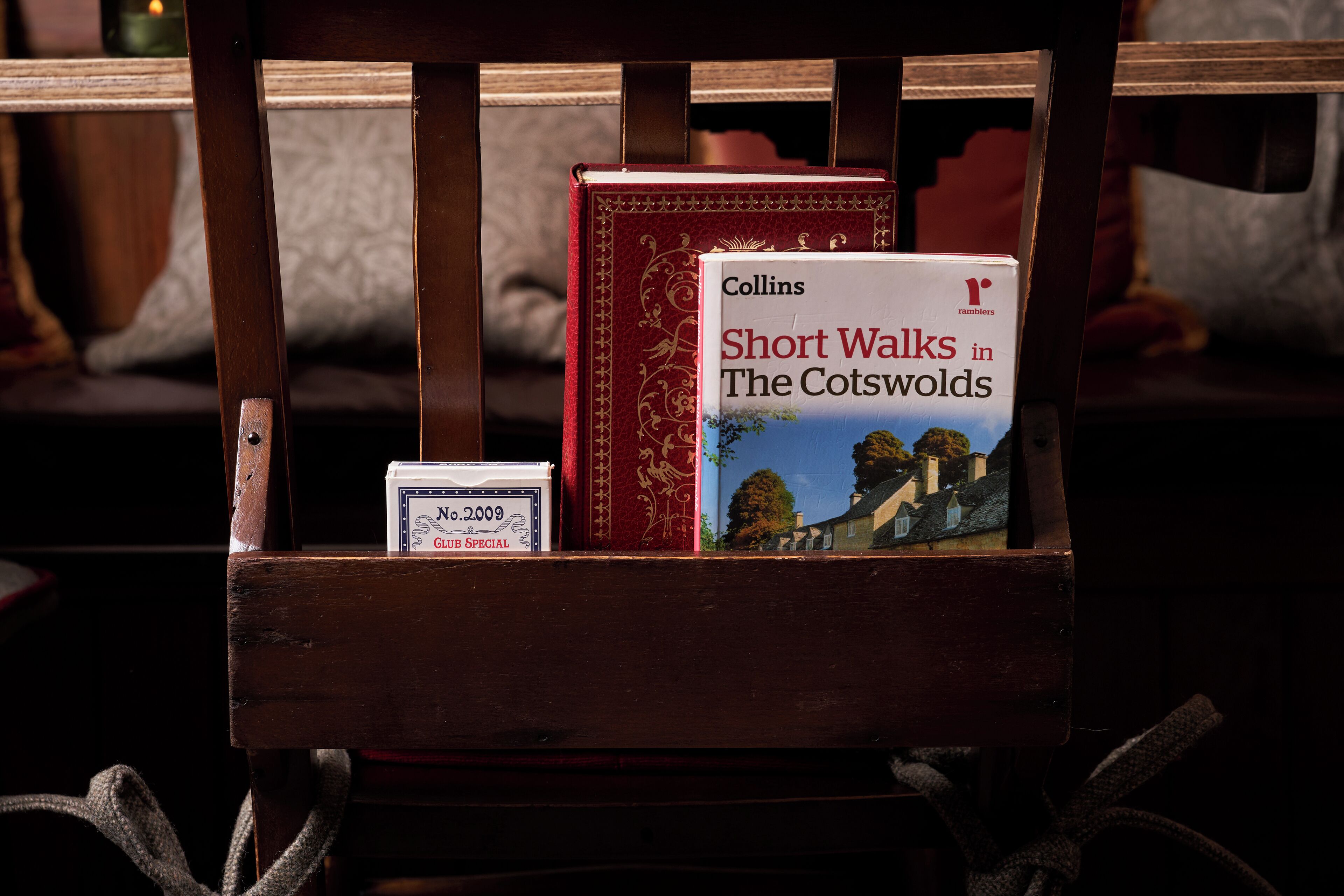 A wooden chair with a book titled 'Short Walks in the Cotswolds' and a small box labeled 'No. 2009 GLASS SPECIAL'.