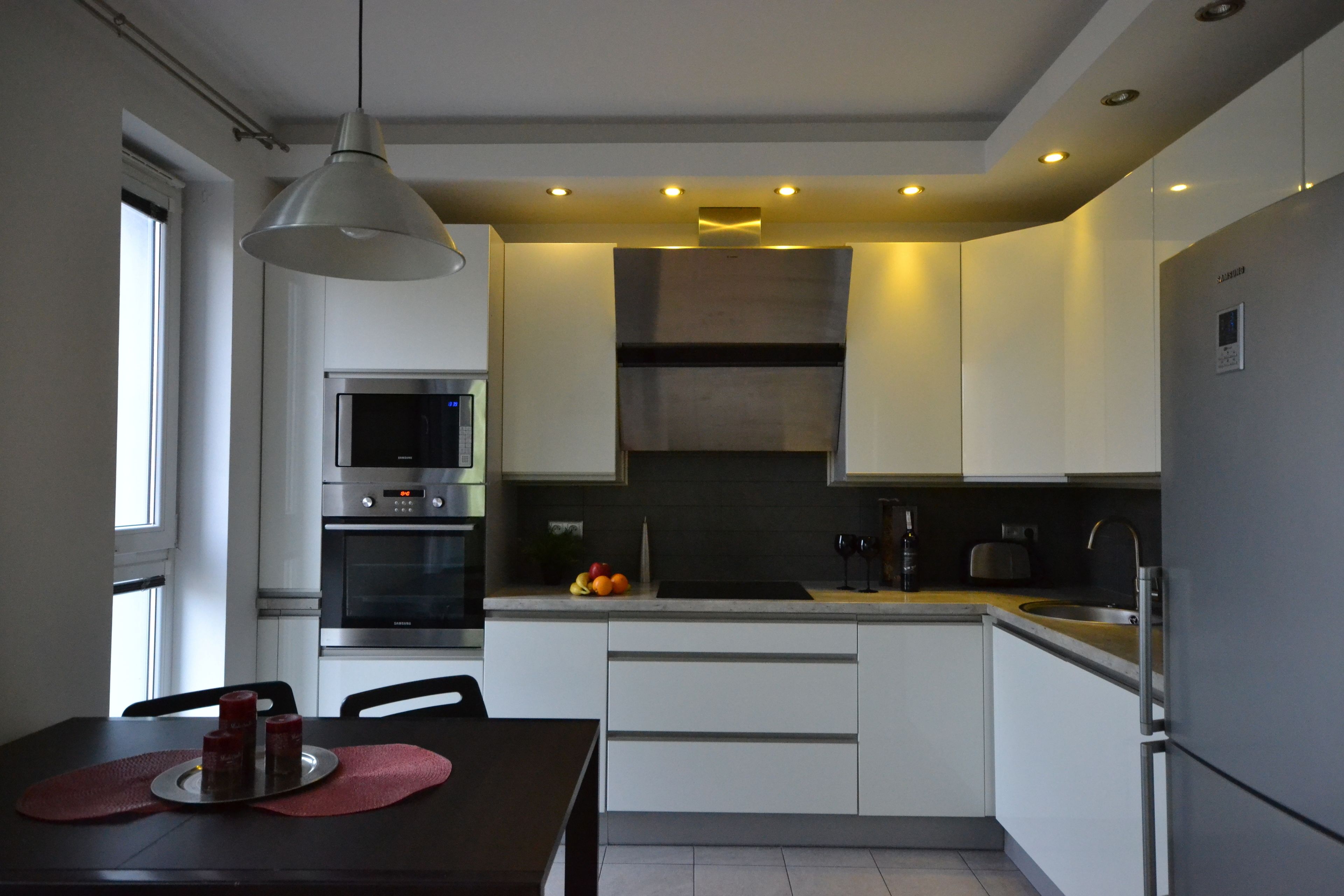 A modern kitchen with white cabinets, stainless steel appliances, and a dining area with a table and chairs.