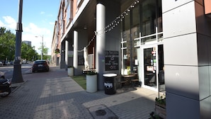 A modern building with a storefront, outdoor seating, and a sign advertising a 50% discount on breakfast. - Senator Warsaw Apartments (Warsaw)