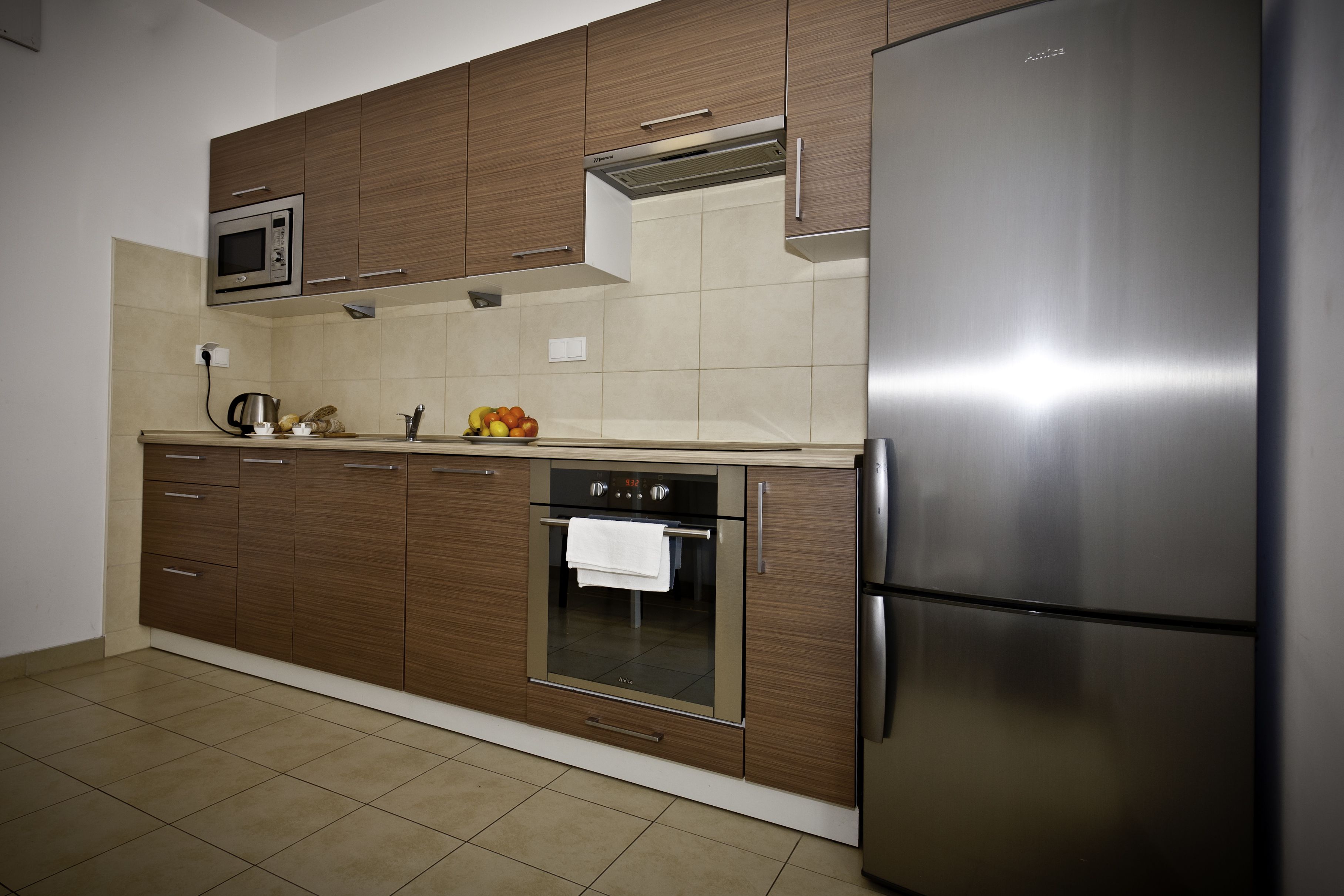 Een moderne keuken met roestvrijstalen apparatuur, houten keukenkastjes en een betegelde achterwand.