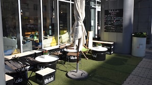 An outdoor seating area with tables and chairs, a standing umbrella, and a chalkboard menu. - Senator Warsaw Apartments (Warsaw)