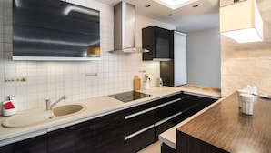 A modern kitchen with a large island, black cabinetry, and a white tiled backsplash. - Senator Warsaw Apartments (Warsaw)