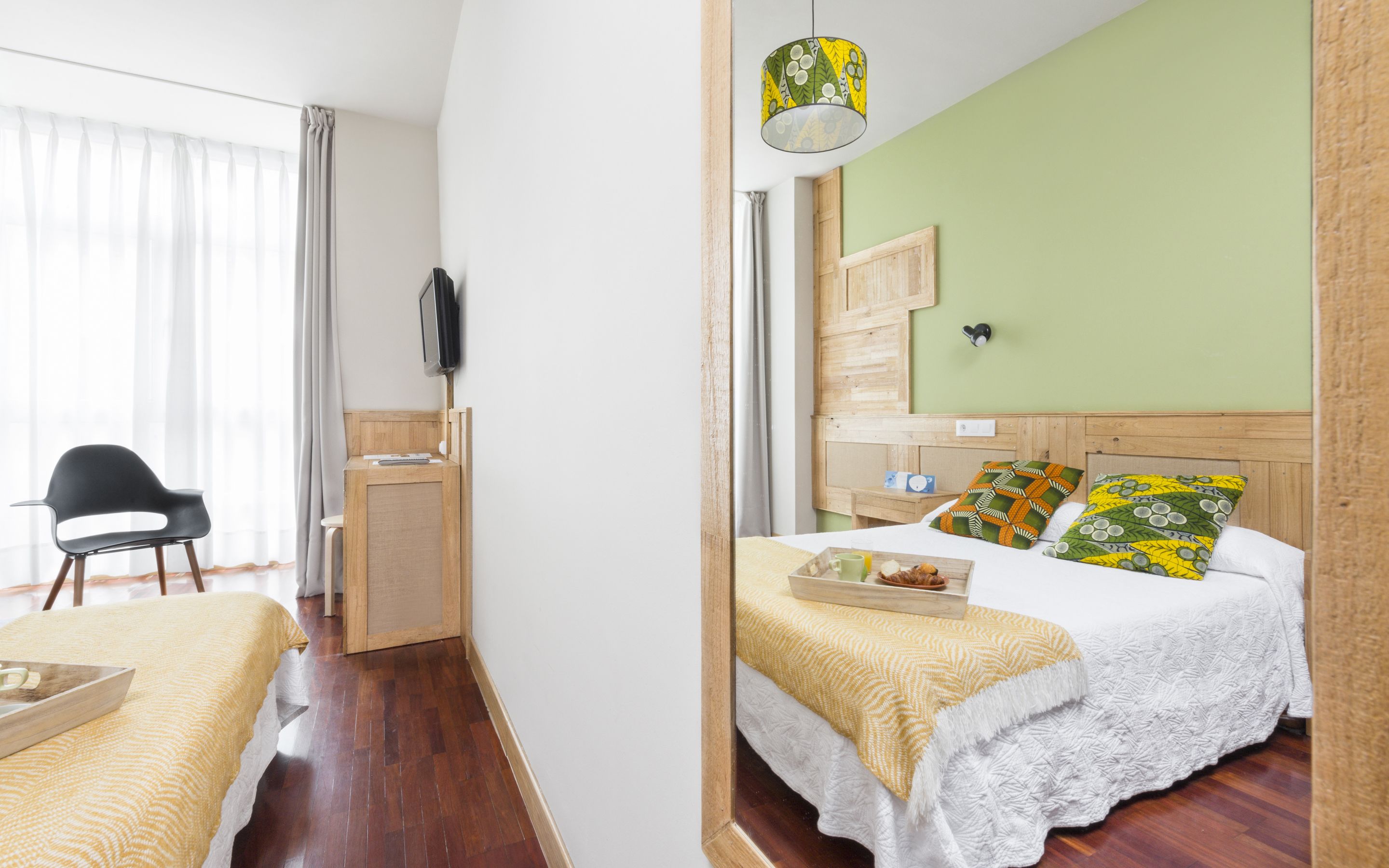 A hotel room with a bed, bedside table, and a chair.