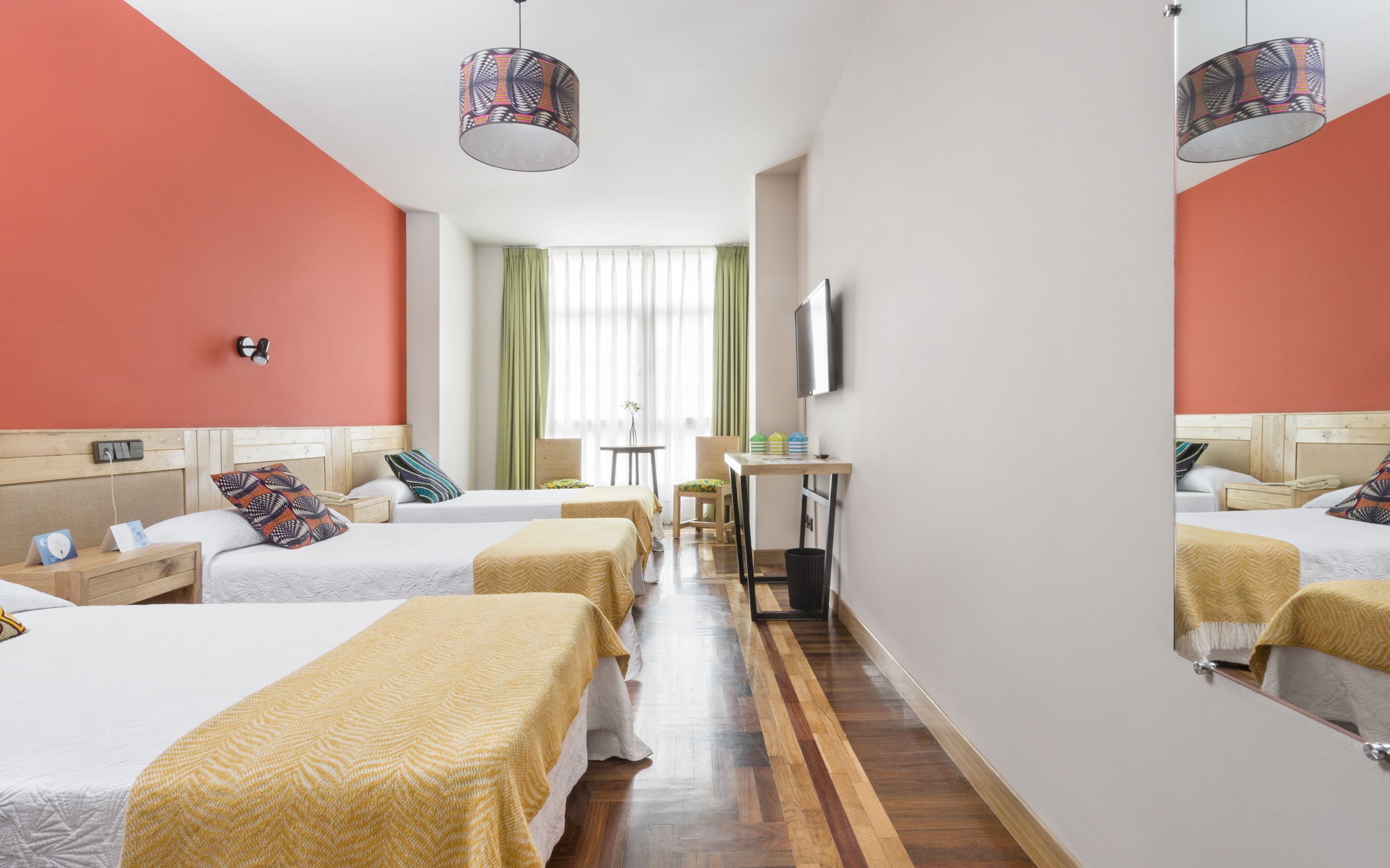 Habitación de hotel con dos camas, un escritorio, una silla, un televisor y un espejo.