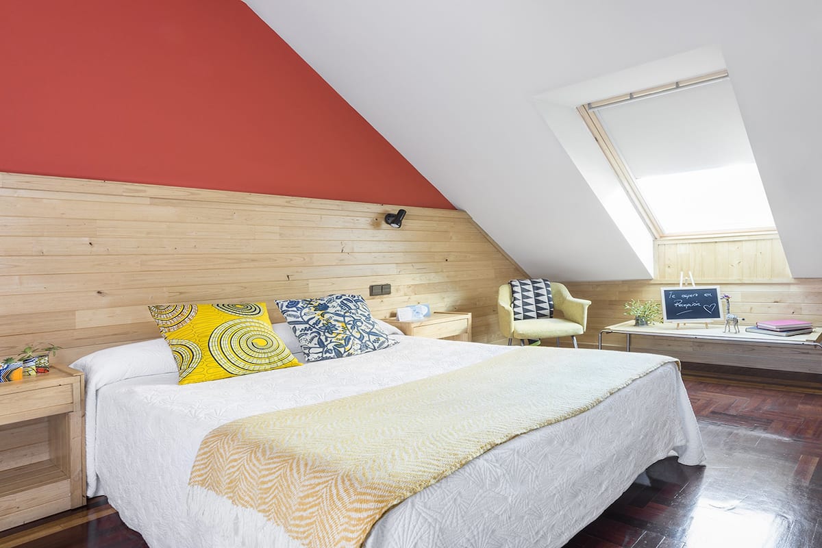 Quarto com cama, escrivaninha, cadeira e janela.