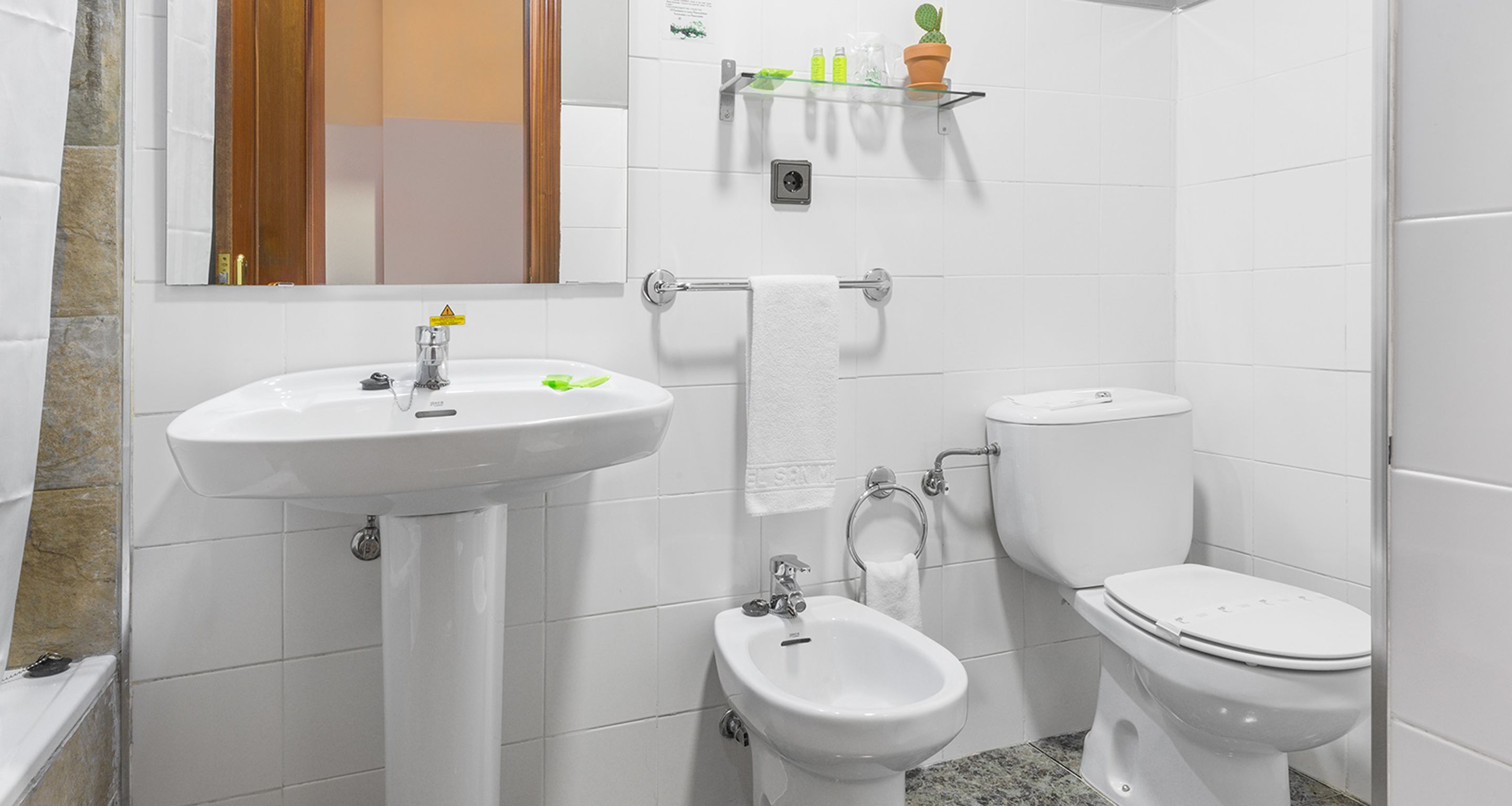 A bathroom with a sink, bidet, and toilet.