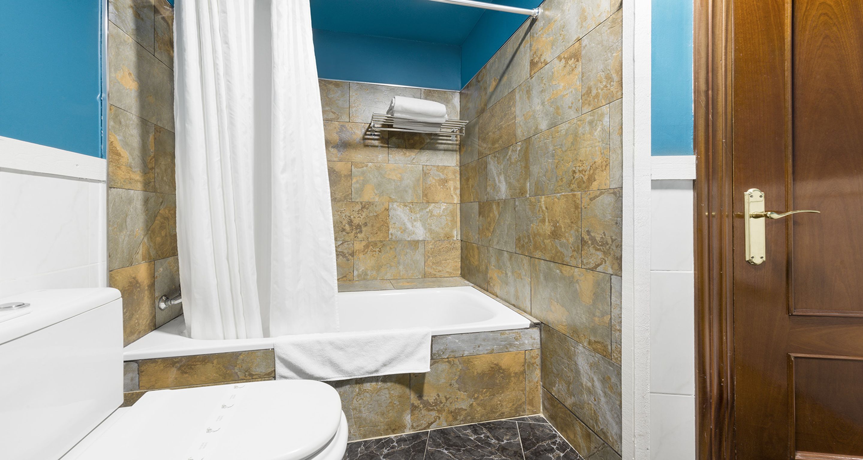 A bathroom with a bathtub, toilet, and shower curtain.