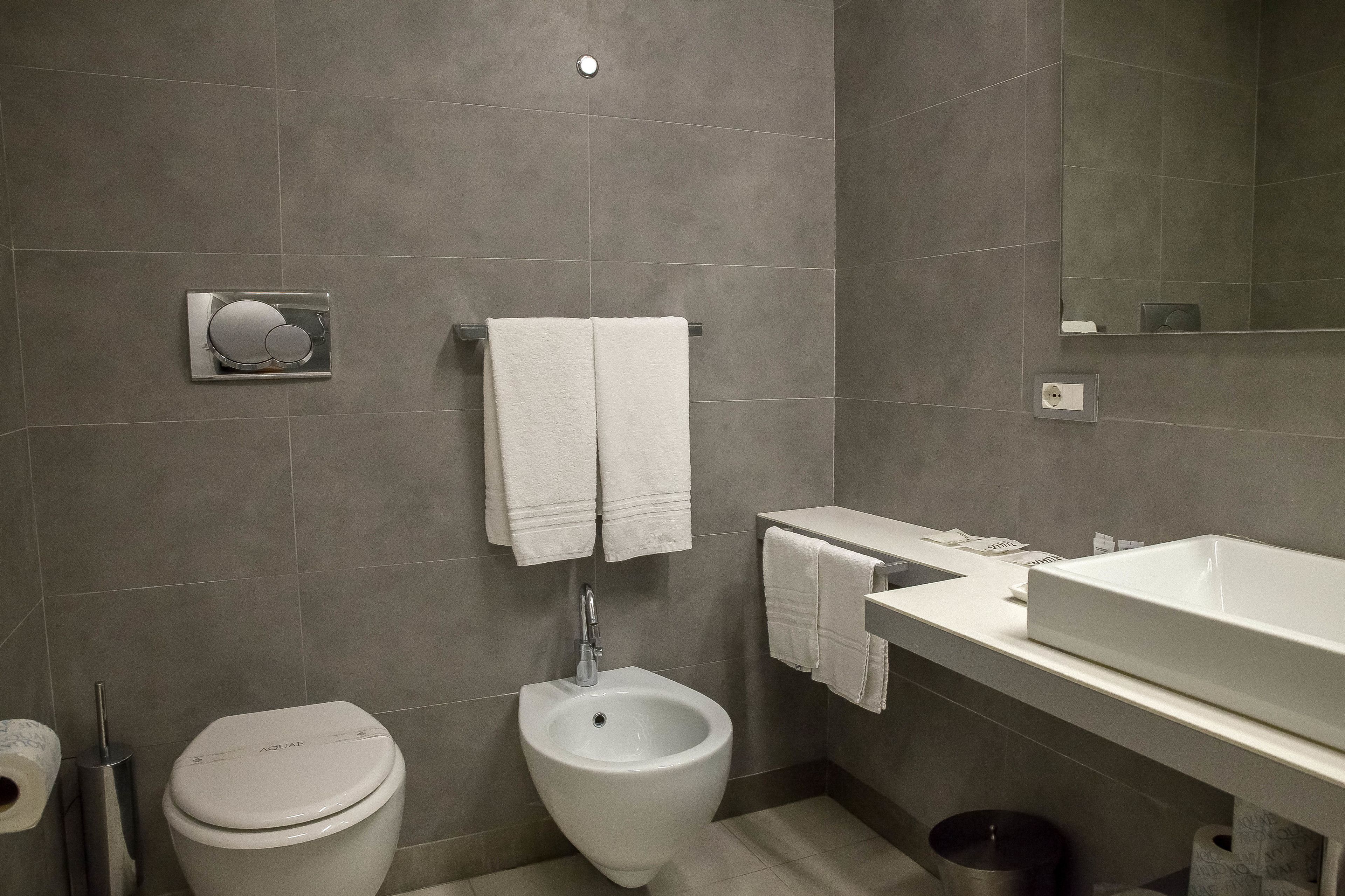 A modern bathroom with a bidet, toilet, and a large mirror.