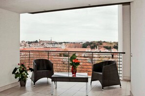 A balcony with two wicker chairs, a small table, and a vase of flowers. - Lungotevere Suite (Rome)