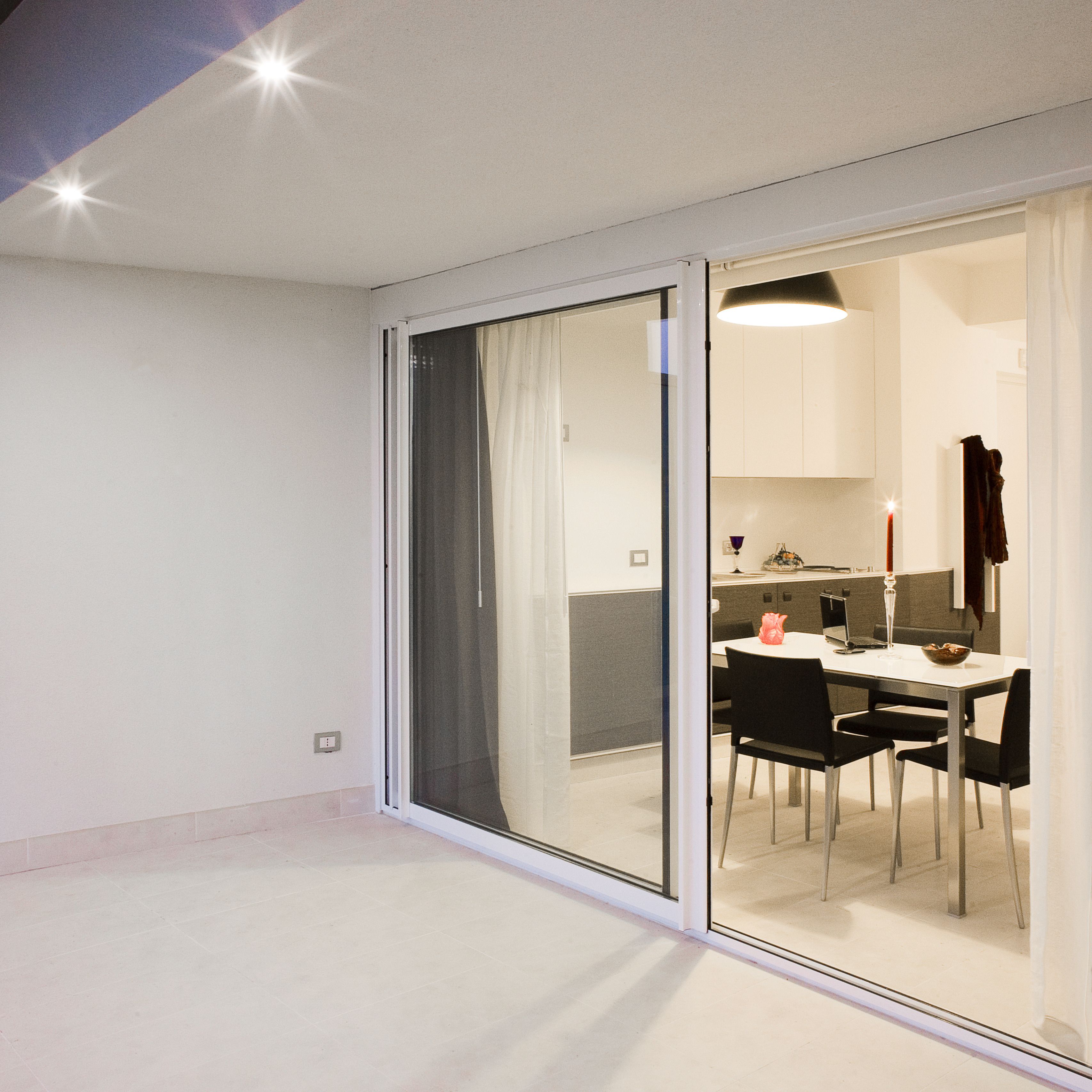 A modern interior with a dining area, a kitchen, and a sliding glass door leading to an outdoor space.