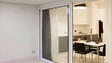A modern interior with a dining area, a kitchen, and a sliding glass door leading to an outdoor space.