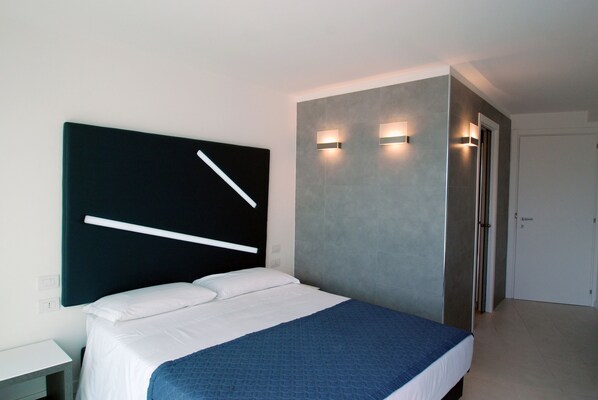 A modern hotel room with a large bed, a bedside table, and a wall-mounted light fixture. - Lungotevere Suite (Rome)
