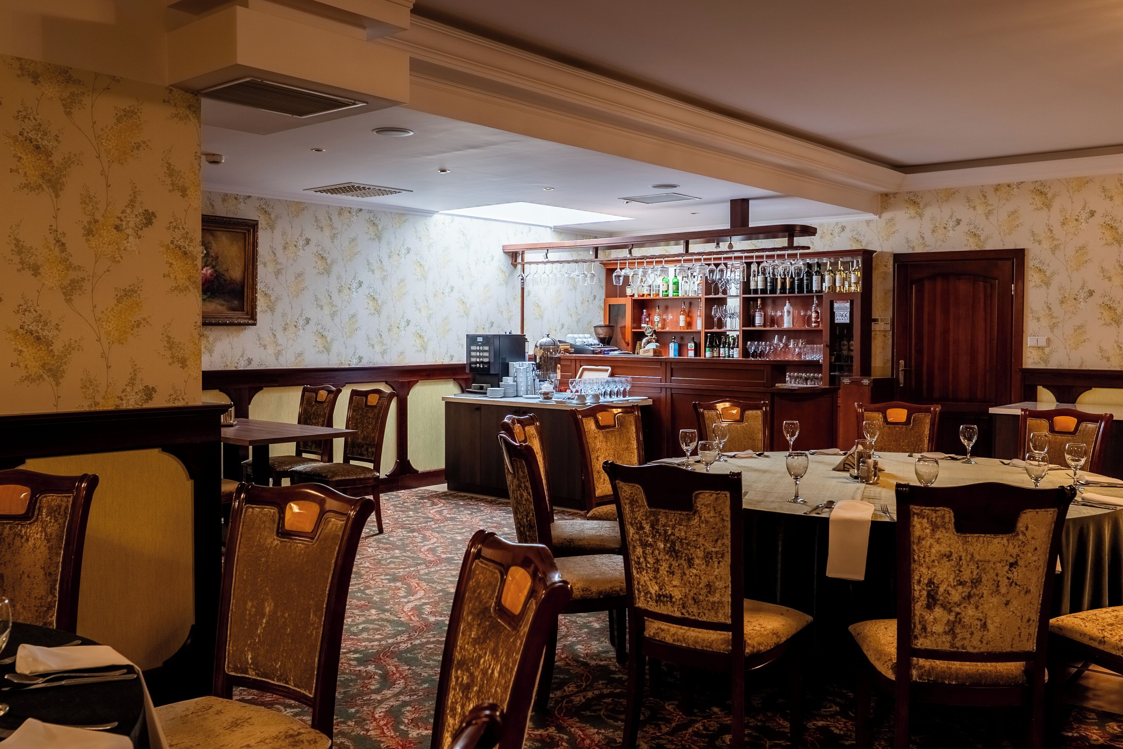 A restaurant with a bar area, wooden chairs, and tables set for dining.