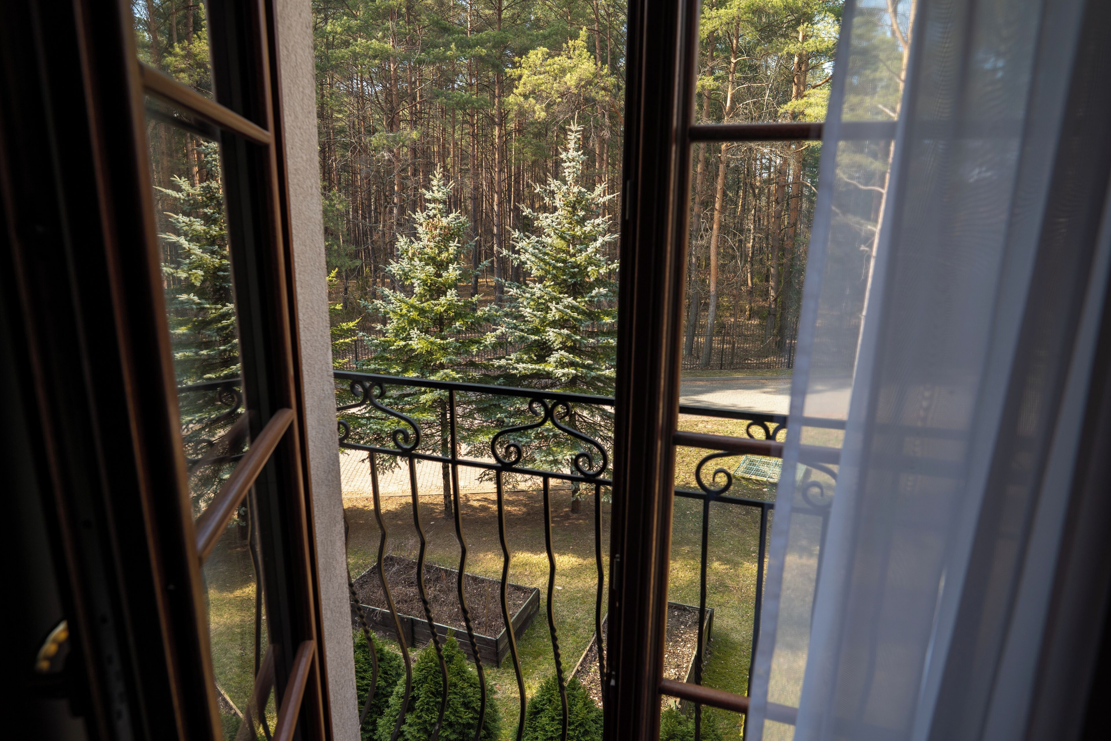 A balcony with a view of a forested area, a metal railing, and a raised garden bed.