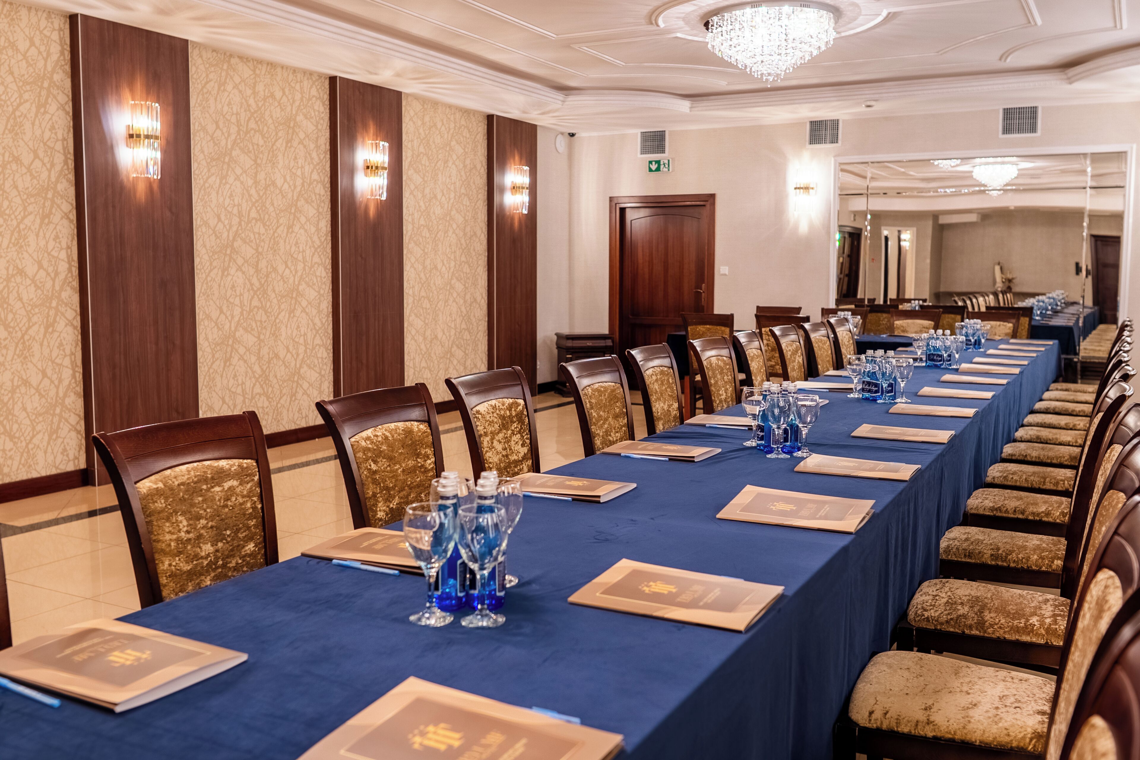 Un salón de conferencias con una larga mesa, sillas y una araña.