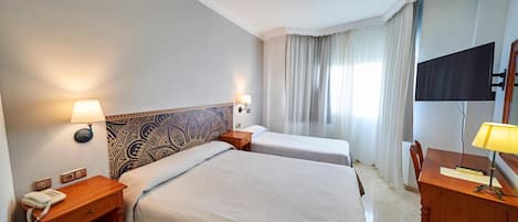 A hotel room with two beds, a desk, a chair, a TV, and a telephone.