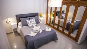A neatly arranged bedroom with a bed, bedside tables, a mirror, and a wardrobe. - Hotel Bajamar (Nerja)