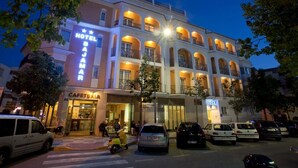 A multi-story hotel with a prominent sign, a cafe, and several parked cars. - Hotel Bajamar (Nerja)