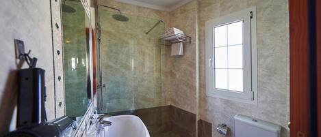 A bathroom with a glass-enclosed shower, a sink, a toilet, and a window.