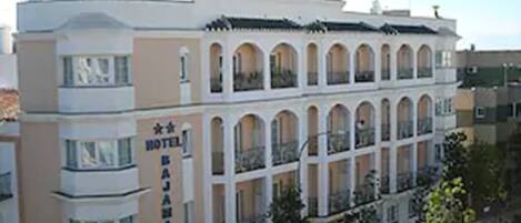 Un hotel con un llamativo letrero que dice “HOTEL” en el techo, varios balcones y un estilo arquitectónico clásico.