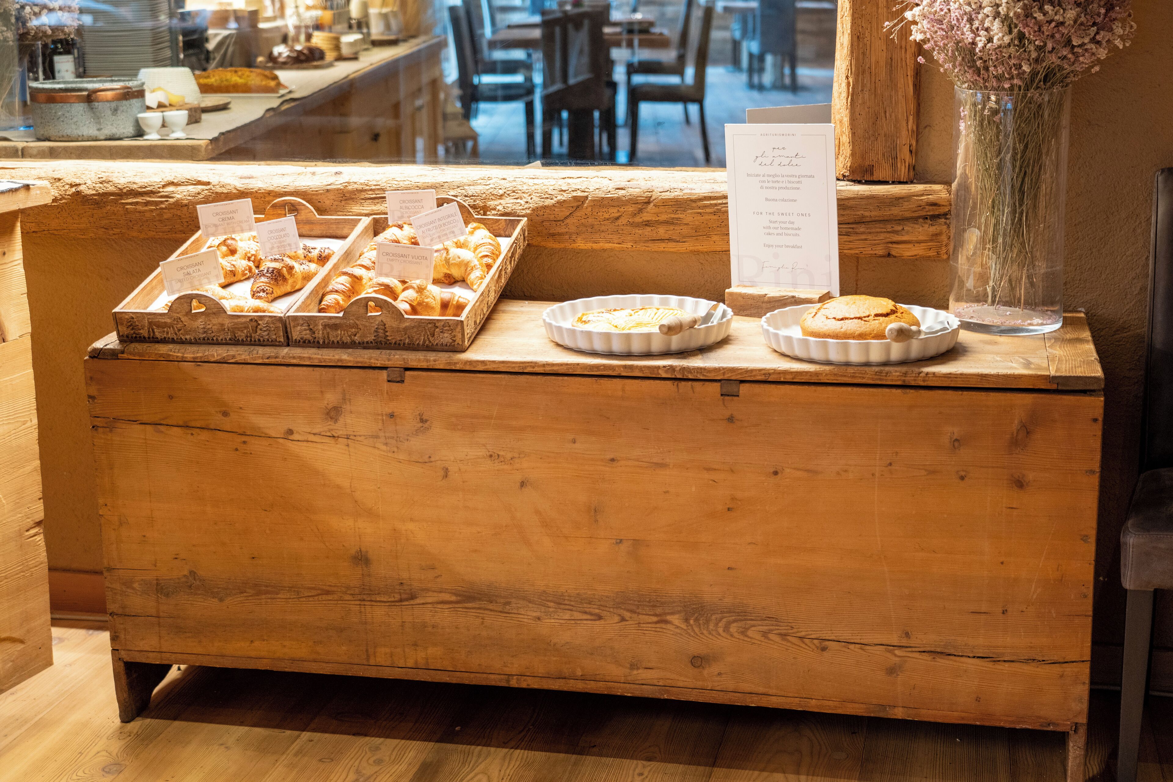 Un comptoir en bois où sont exposées des pâtisseries, ainsi qu’un menu.