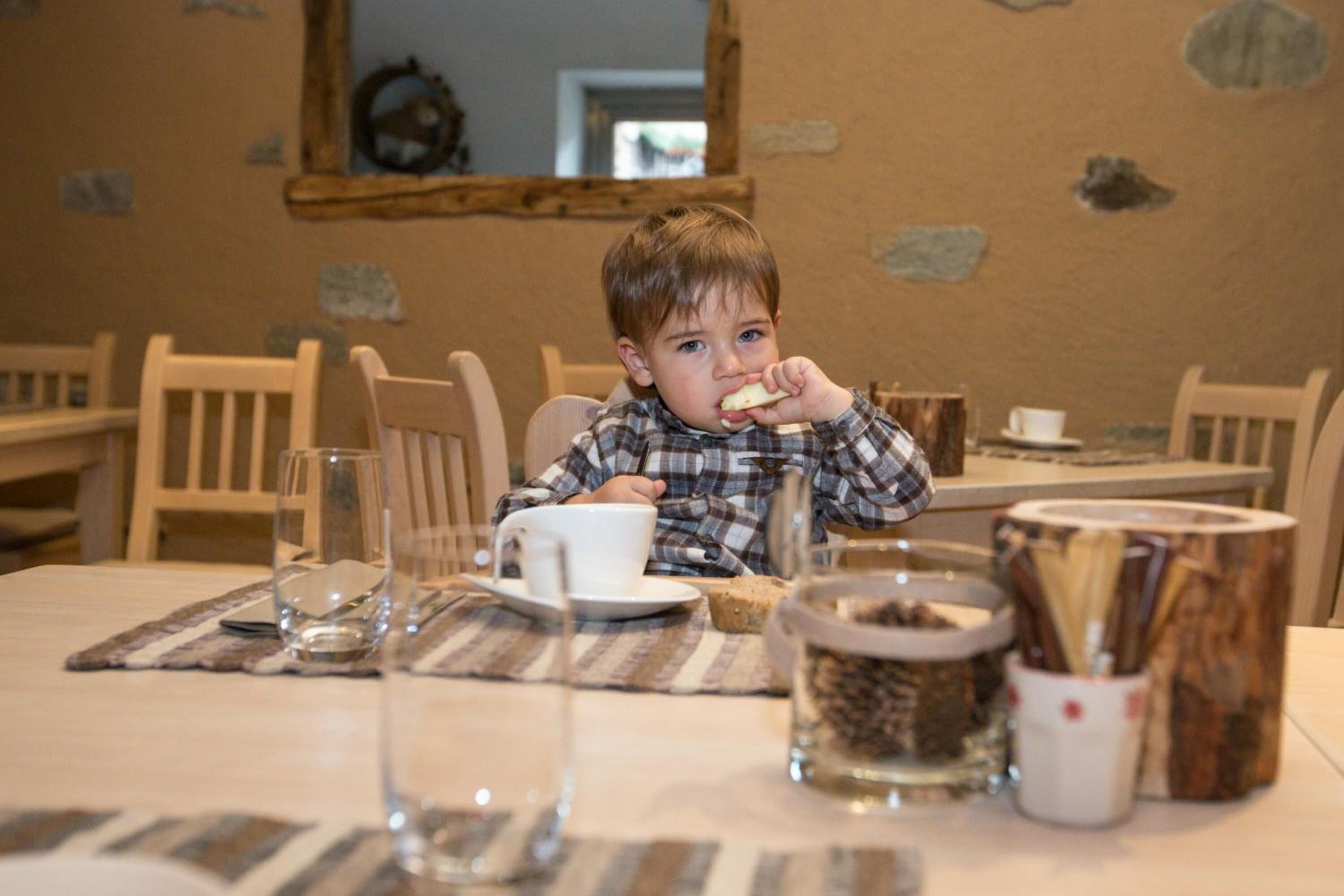 Un enfant est assis à une table devant une tasse, un verre et un bocal rempli de graines.
